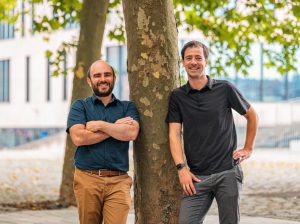 The 2 founders of Carbon+Alt+Delte leaning against a tree.